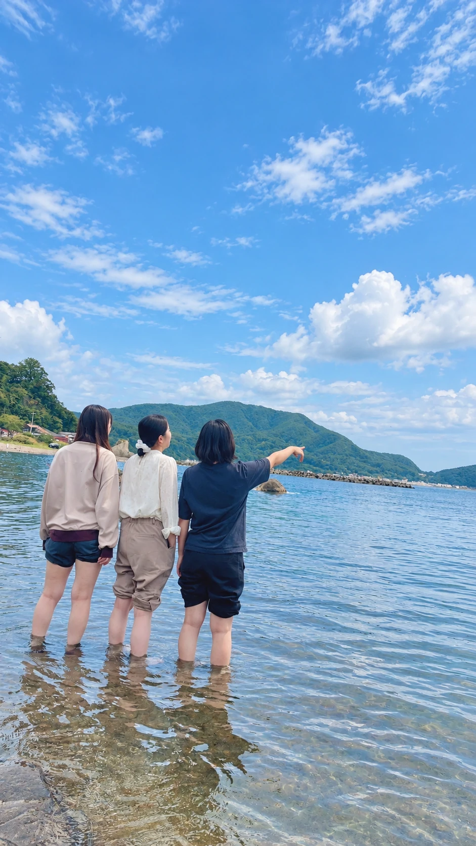 海辺で水に足を浸し、景色を眺める3人