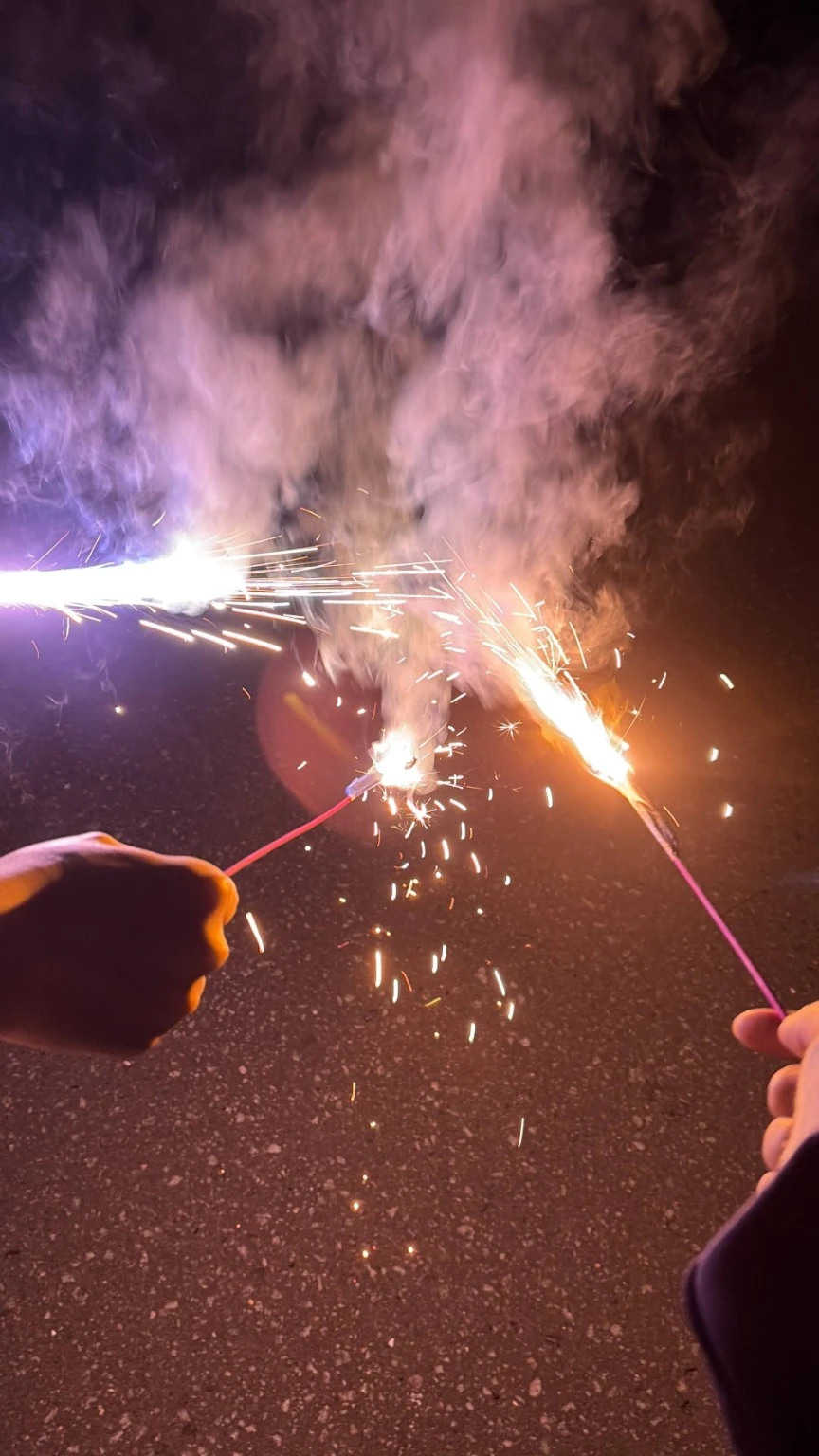 夏の夜、手に持った花火から広がる光と煙